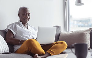 Woman sitting on her couch with her laptop on her lap. Sandy Spring Bank Mortgage Refinancing