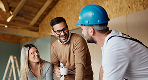 Man and woman talking to a man in a hard hat discussing plans in a room under construction. Sandy Spring Bank Home Equity Loans