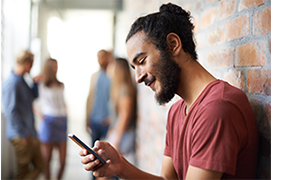 Man smiling as he looks at his cell phone. Sandy Spring Bank Personal Overdraft Services. Take control of your finances by understanding overdraft services and other strategies you can use to help you manage your accounts. 